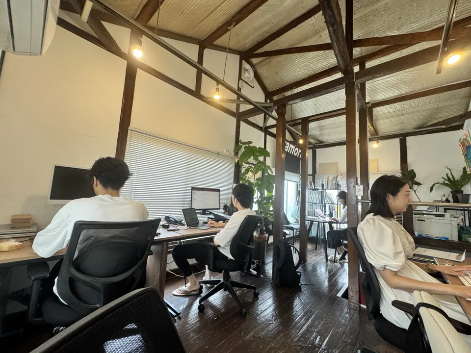 木の梁と観葉植物のある原宿本社で働くメンバー